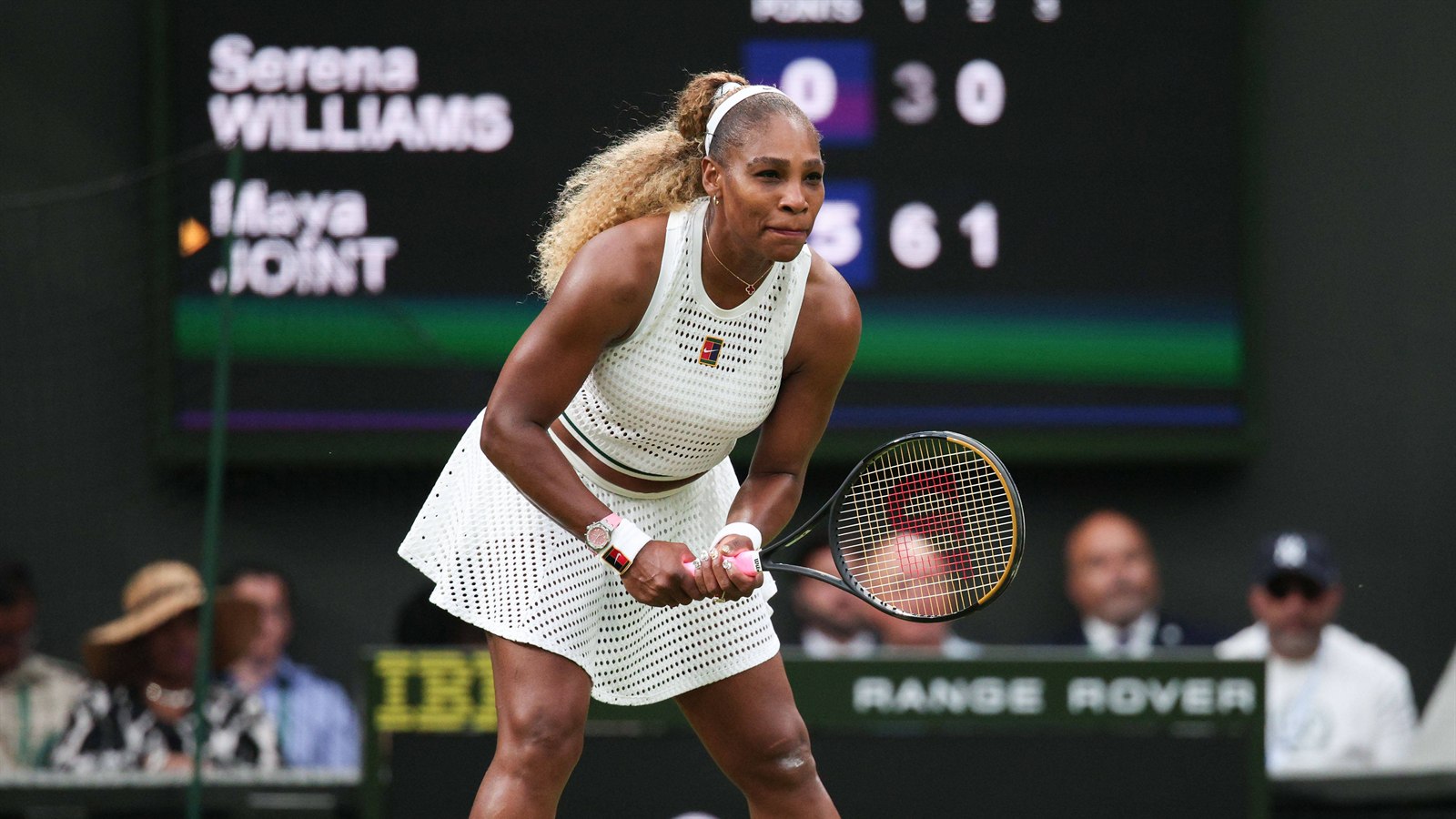 Serena Williams waits to receive serve in front of the Wimbledon scoreboard showing points and games